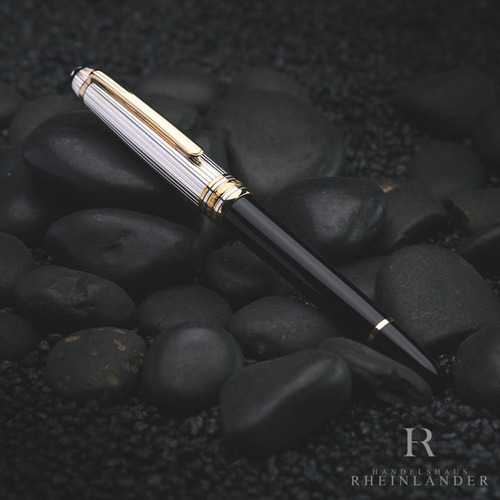 Schwarzer Rollerball mit silberner Kappe auf dunkelgrauen Steinen liegend fotografiert