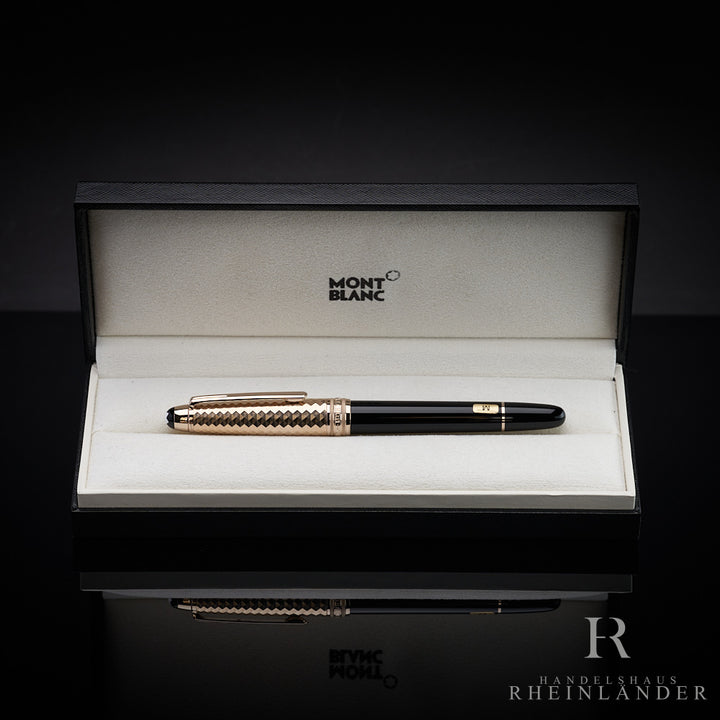 Schwarzer Füller mit goldener Musterkappe liegt in offener Originalbox vor dunkelgrauem Hintergrund