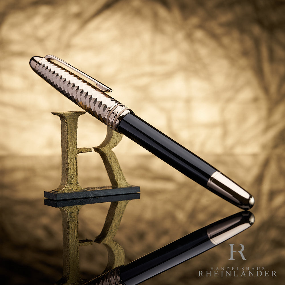 Schwarzer Rollerball mit goldener Kappe an 3D-Buchstabe R lehnend vor goldenem Knitteroptik-Hintergrund