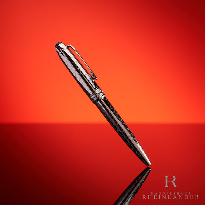 Silberner Kugelschreiber halb aufrecht stehend vor rotem Hintergrund fotografiert