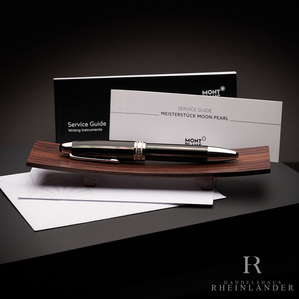 Schwarzer Rollerball liegt auf Holzbrettchen, dahinter steht der Serviceguide, Hintergrund dunkelgrau