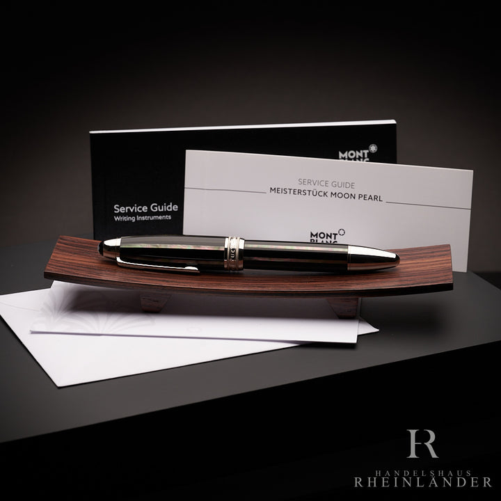 Schwarzer Rollerball liegt auf Holzbrettchen, dahinter steht der Serviceguide, Hintergrund dunkelgrau