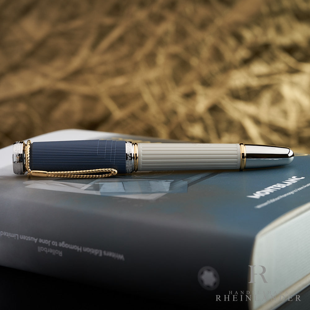 Cremefarbener Rollerball mit blauer Kappe liegt auf Editionsbox, seitlich vor goldenem Hintergrund fotografiert