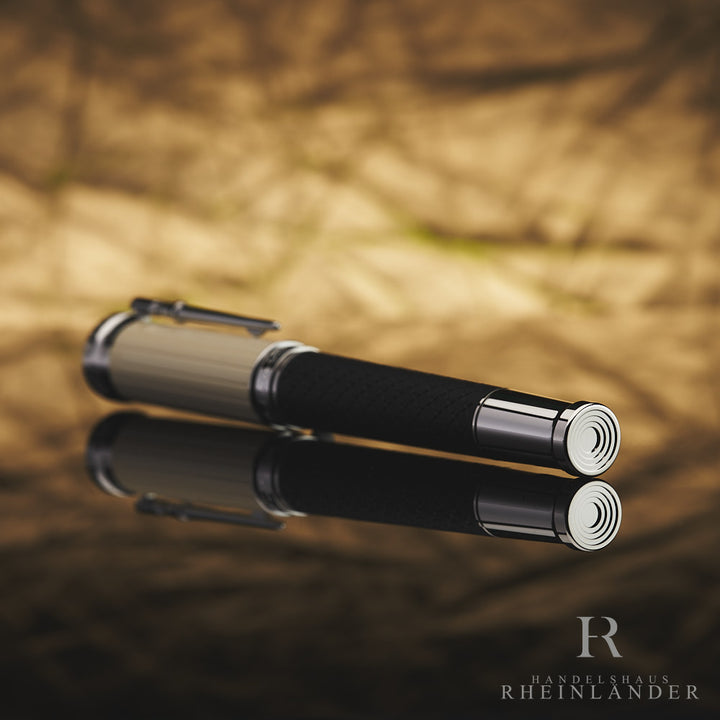 Schwarzer Rollerball mit beiger Kappe liegt mit silbernen Konus in Richtung Kamera positioniert