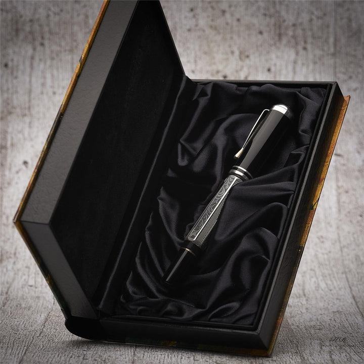 Silber-schwarzer Füller liegt in offener, halb aufgestellter Originalbox vor hellgrauem Holzoptik-Hintergrund