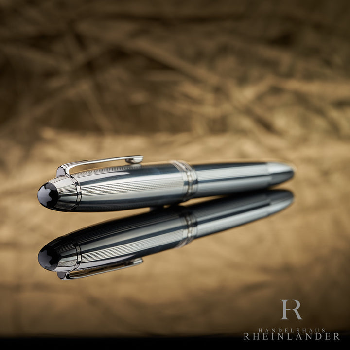 Kappenkopf mit Guilloche und Montblanc Emblem des LeGrand Pure Silver Solitaires liegend vor goldenem Hintergrund