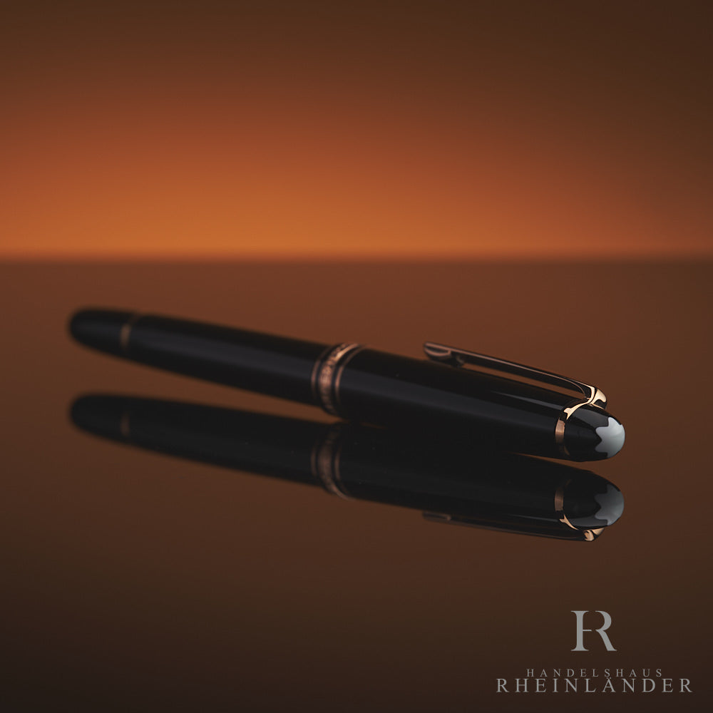 Schwarzer Rollerball mit rotgoldenen Beschlägen liegt schräg mit dem Kappenkopf zur Kamera, das Emblem ist sichtbar