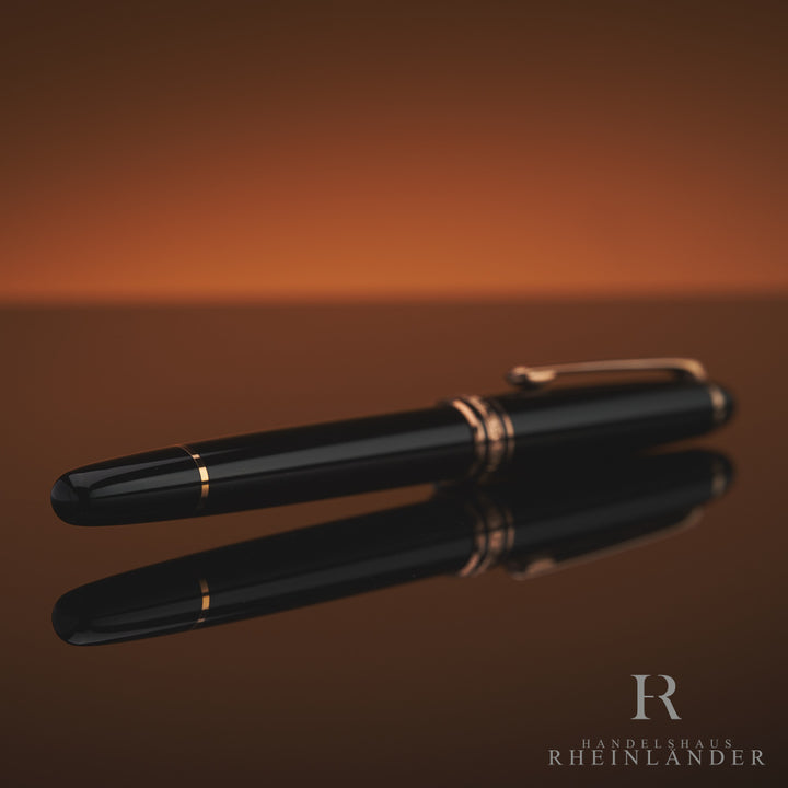 Schwarzer Rollerball mit rotgoldenen Beschlägen liegt schräg mit dem Konus voran zur Kamera