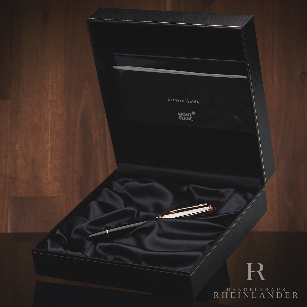 Schwarzer Rollerball mit silberner Kappe in offener Originalbox liegend vor Holzhintergrund