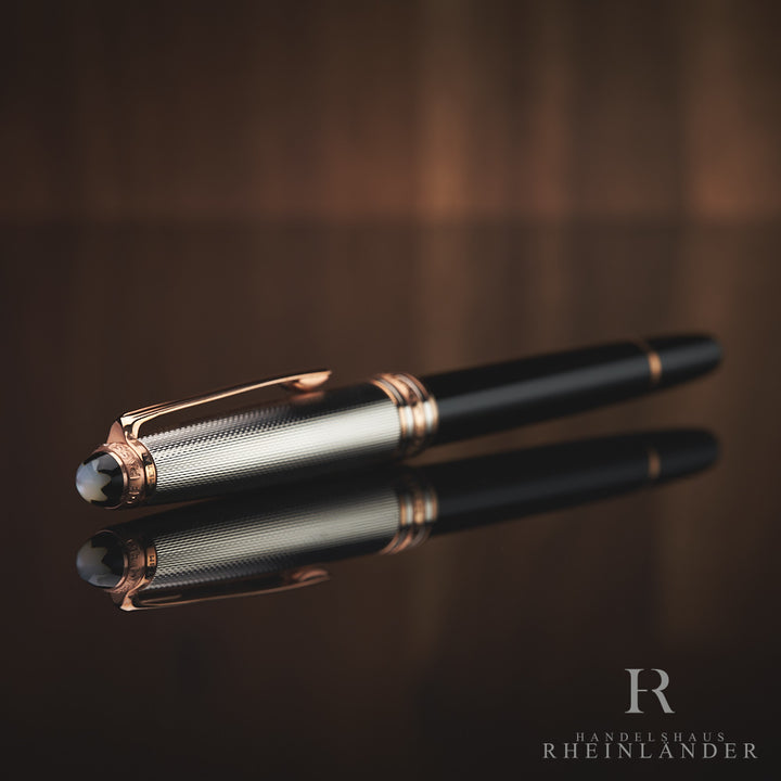 Schwarzer Rollerball mit silberner Kappe und rotgoldenen Beschlägen liegt mit Perlmutt-Emblem schräg zur Kamera gerichtet