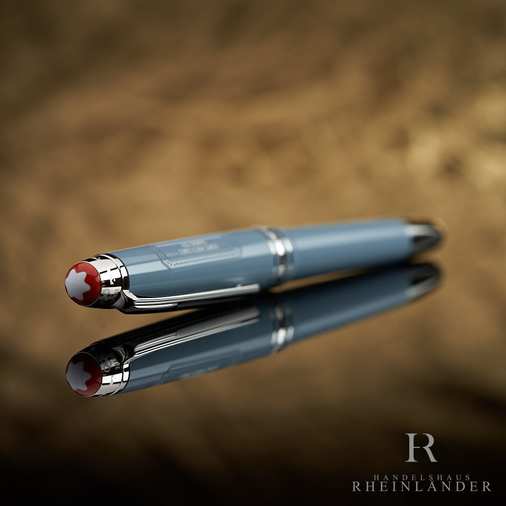 Graublauer Füller liegend auf spiegelnder Oberfläche fotografiert, die Kappe schräg zur Kamera gerichtet