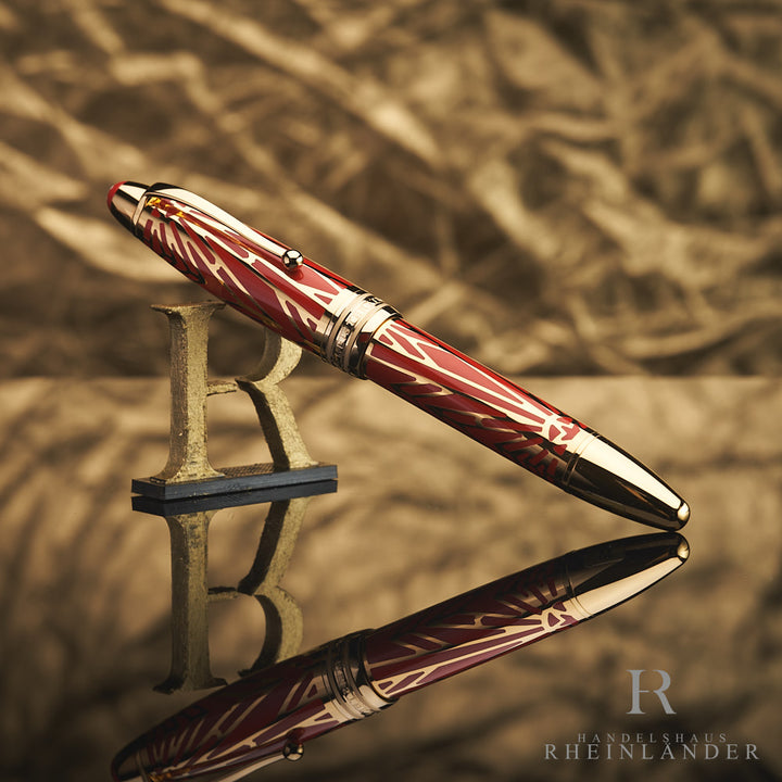 Korallrot-gold gemusterter Rollerball an 3D-Buchstabe R lehnend vor goldenem Hintergrund