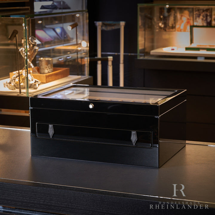 schwarze Montblanc Klavierlack-Schatulle für Schreibgeräte afu schwarzem Tisch mit Lichtern im Hintergrund