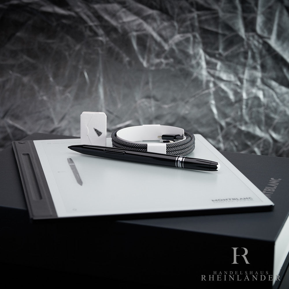 Montblanc Digital Paper Tablet mit Stift und Ladekabel liegend vor silbernem Hintergrund