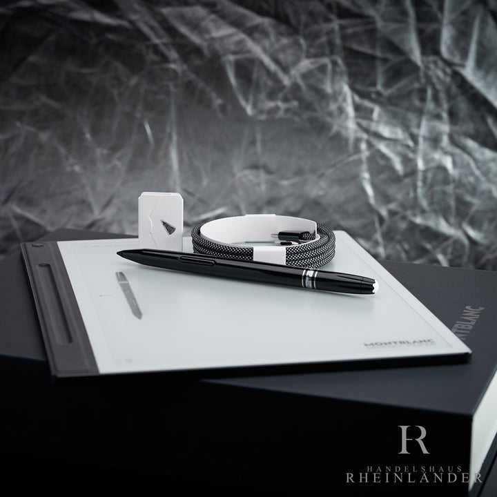 Montblanc Digital Paper Tablet mit Stift und Ladekabel liegend vor silbernem Hintergrund