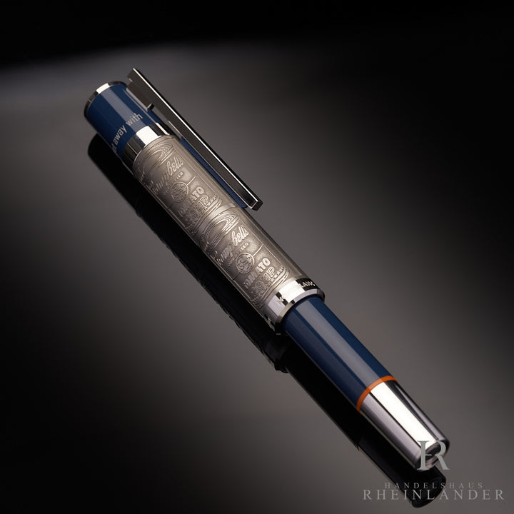 blau grauer Montblanc Andy Warhol Rollerball mit Campbells Tomato Soup Motiv auf der Kappe liegend auf schwarzem Tisch