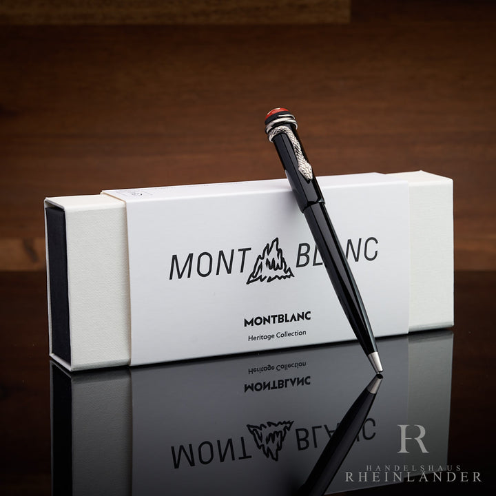 Schwarzer Kugelschreiber lehnt an weisser Montblanc-Box, Untergrund spiegelnd, Hintergrund braunes Holz