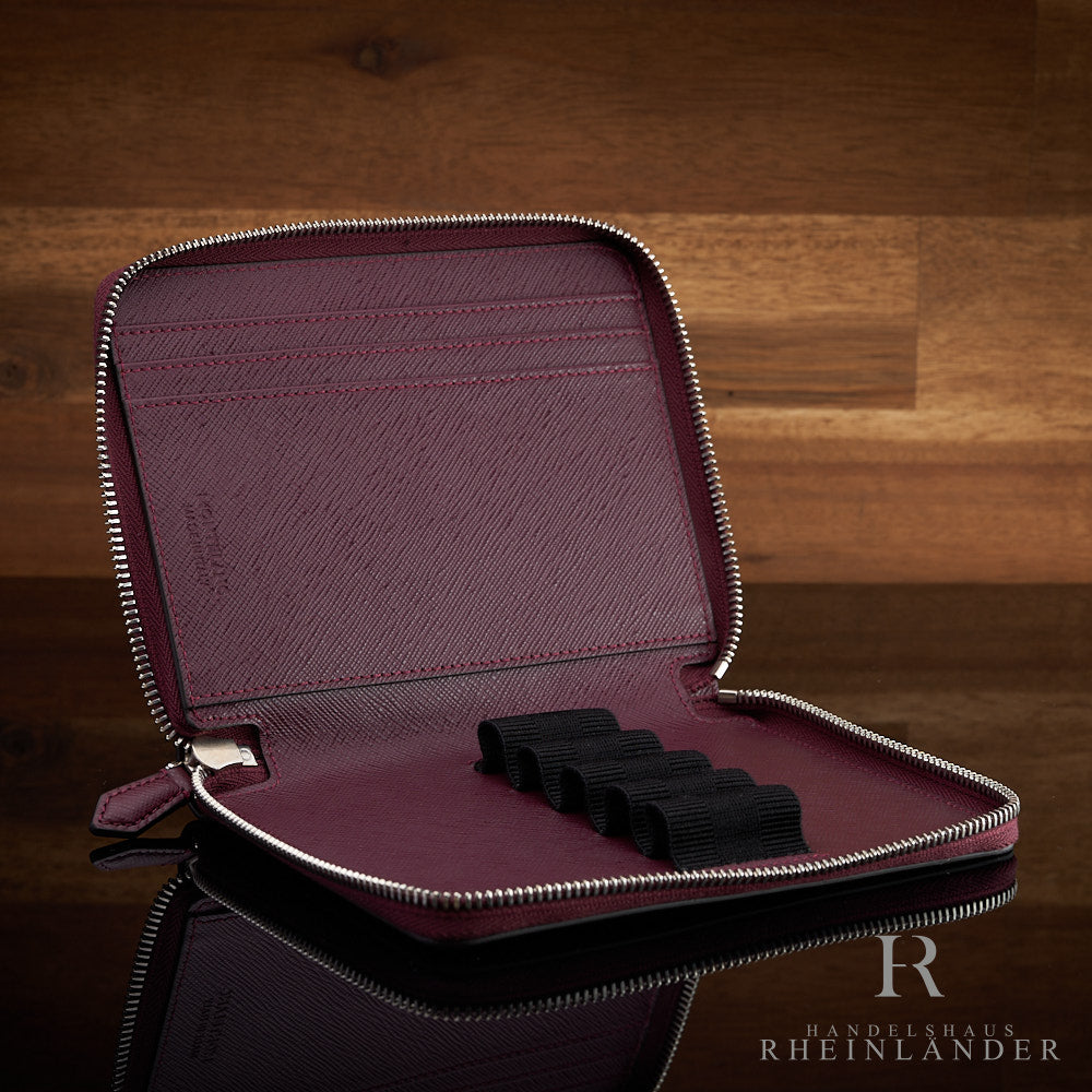 offenes rotes Montblanc Lederetui für fünf Schreibgeräte auf schwarzem Tisch  und hölzernem Hintergrund