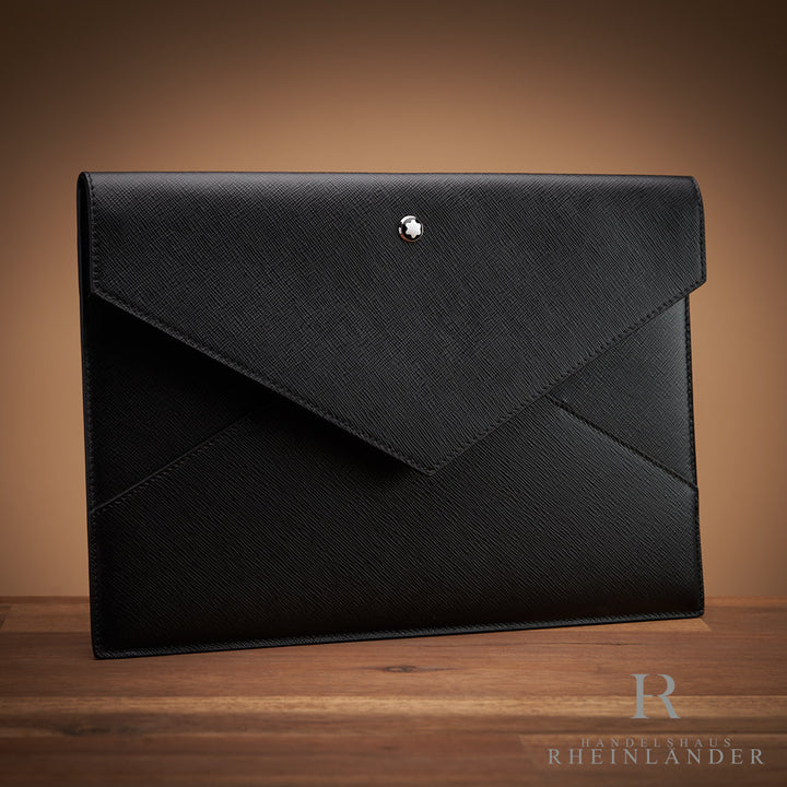 Schwarze Ledertasche von Montblanc in Umschlagform auf Holztisch mit braunem Hintergrund