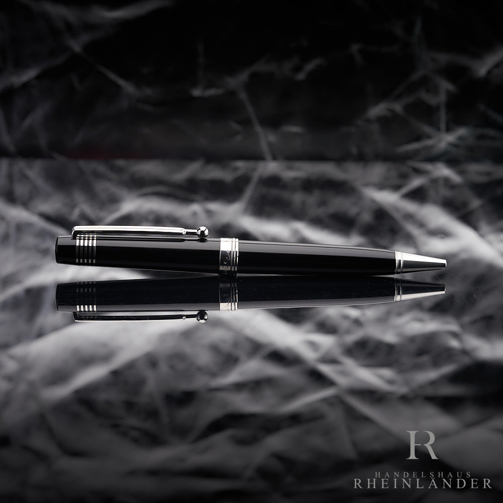 Schwarzer Kugelschreiber mit platinierten Beschlägen liegt horizontal auf spiegelndem Untergrund