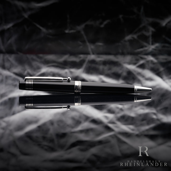 Schwarzer Kugelschreiber mit platinierten Beschlägen liegt horizontal auf spiegelndem Untergrund