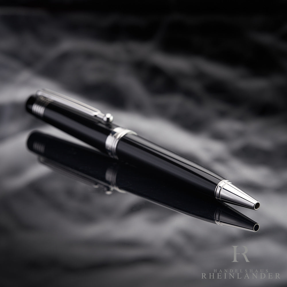 Schwarzer Kugelschreiber liegt schräg auf spiegelnder Oberfläche, die Schreibspitze ist zur Kamera gerichtet