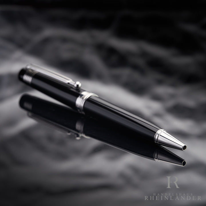 Schwarzer Kugelschreiber liegt schräg auf spiegelnder Oberfläche, die Schreibspitze ist zur Kamera gerichtet