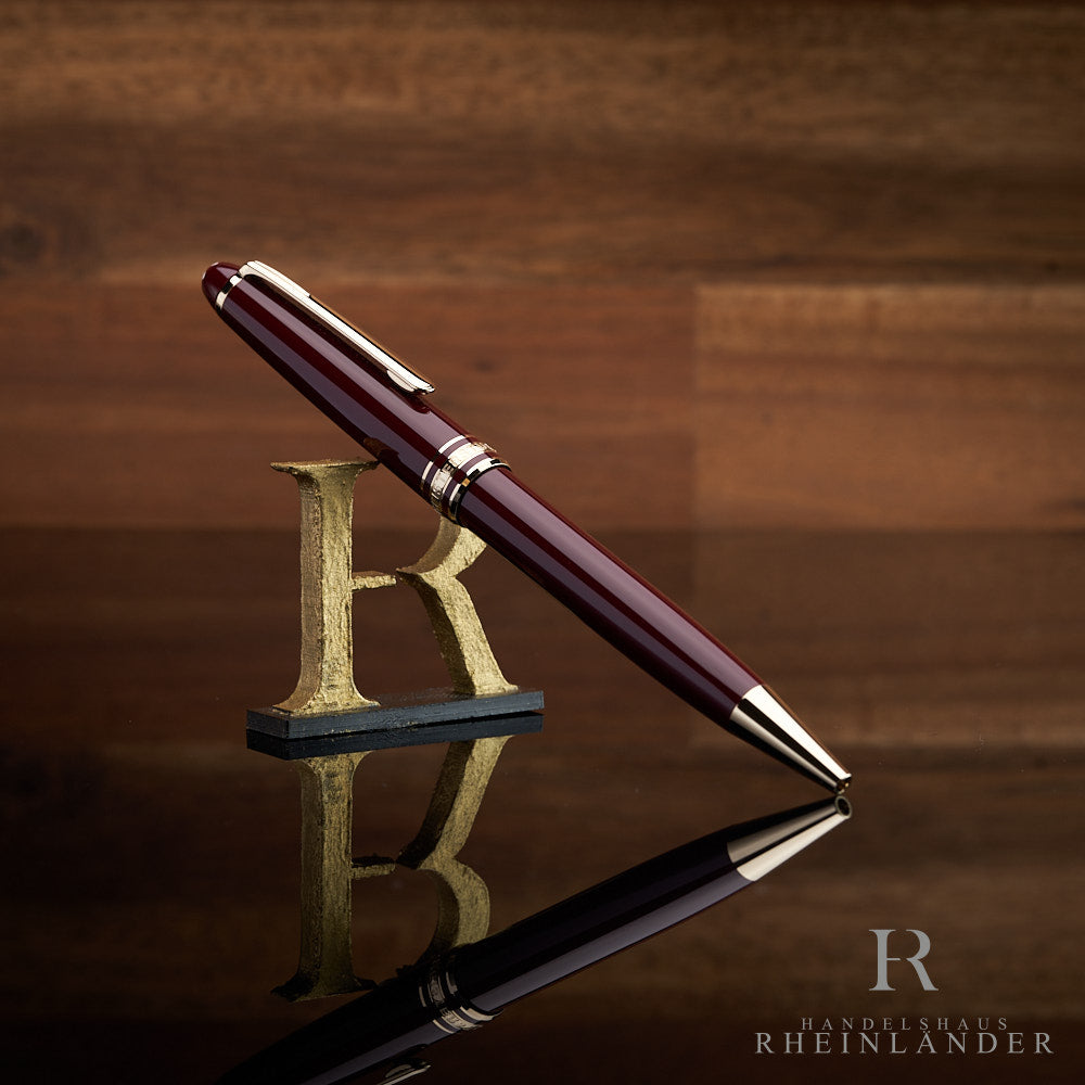 Burgunderroter Montblanc Kugelschreiber angelehnt an das  Handelshaus Rheinländer Logo vor hölzernem Hintergrund