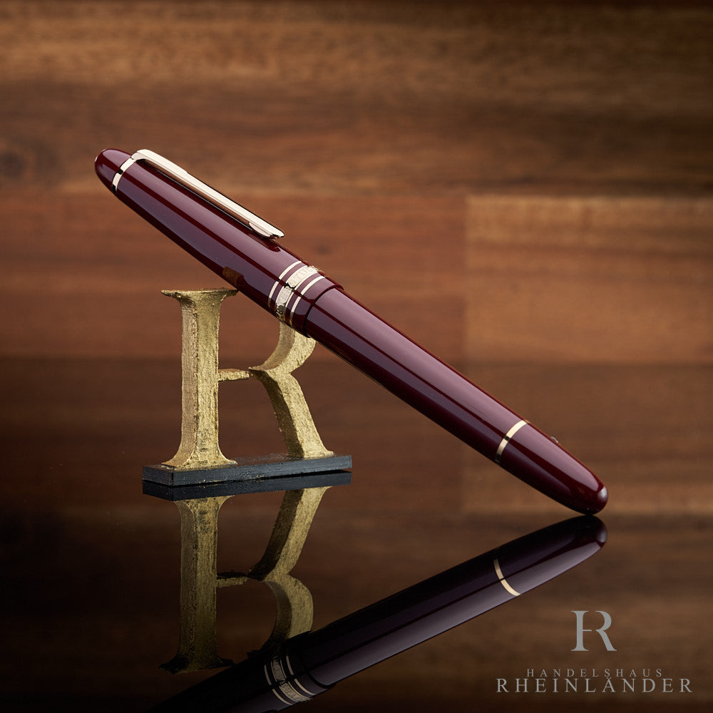 Montblanc Füller in burgunderrot angelehnt an das Handelshaus Rheinländer Logo vor hölzernem Hintergrund