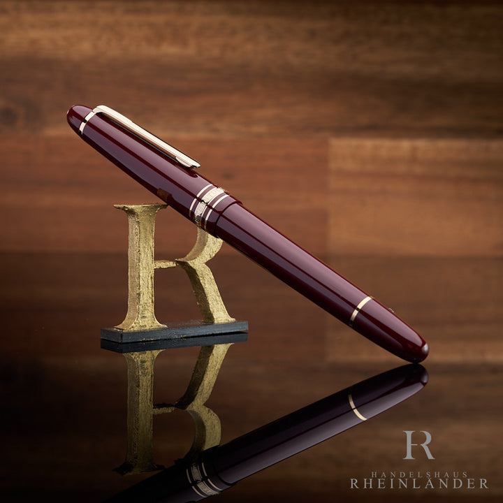 Montblanc Füller in burgunderrot angelehnt an das Handelshaus Rheinländer Logo vor hölzernem Hintergrund
