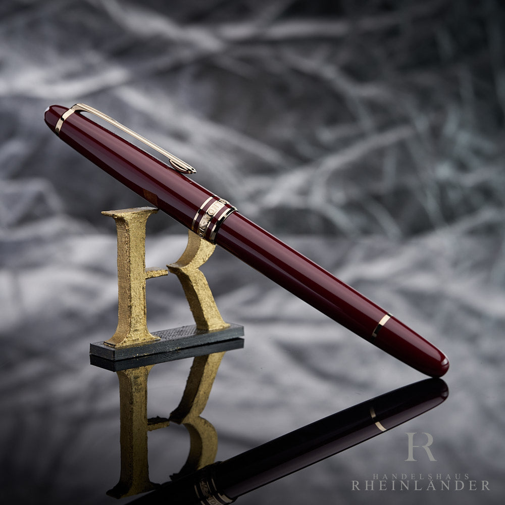 Montblanc Classique Burgundy Rollerball angelehnt an das Handelshaus Rheinländer Logo vor silbernem Hintergrund