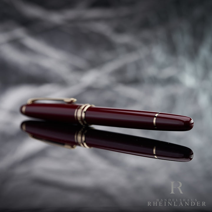 Konusende des Montblanc Classique Burgundy Rollerballs liegend vor silbernem Hintergrund