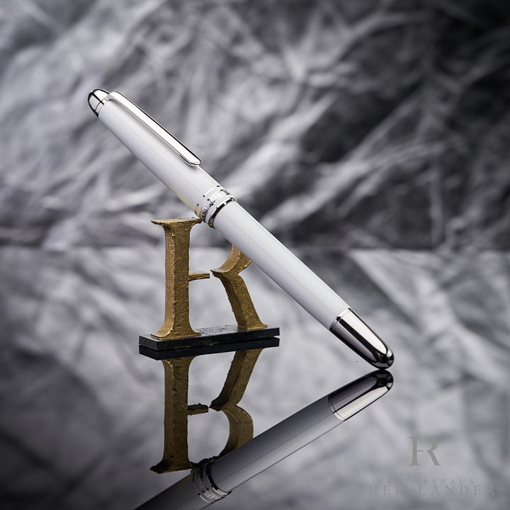 Montblanc Meisterstück Rollerball in weiß angelehnt an das Handelshaus Rheinländer Logo vor silbernem Hintergrund