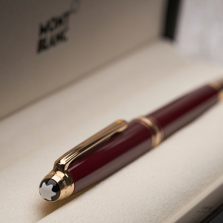 goldener Kappenkopf mit Clip und bordeauxroter Kappe des Montblanc Petit Prince Rollerballs in der Originalverpackung