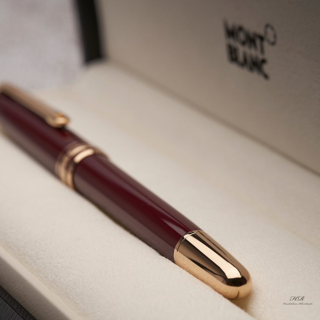goldener Konus und bordeauxroter Schaft des Montblanc Petit Prince Rollerballs in der Originalverpackung liegend
