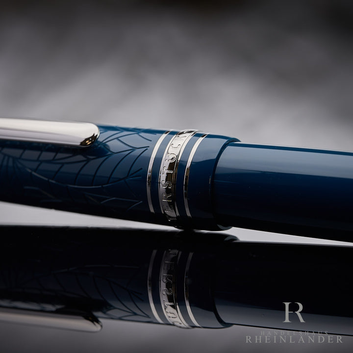 Kappenringe mit Gravuren auf dem blauen Montblanc Romeo & Juliet LeGrand Rollerball liegend vor grauem Hintergrund