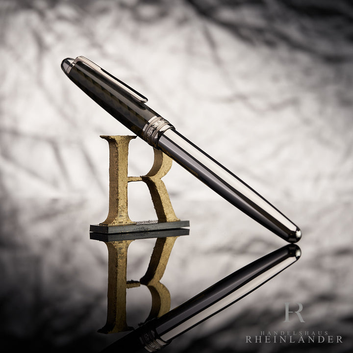 Silberner Rollerball mit dunkler Kappe an 3D-Buchstabe R lehnend vor grauem Hintergrund