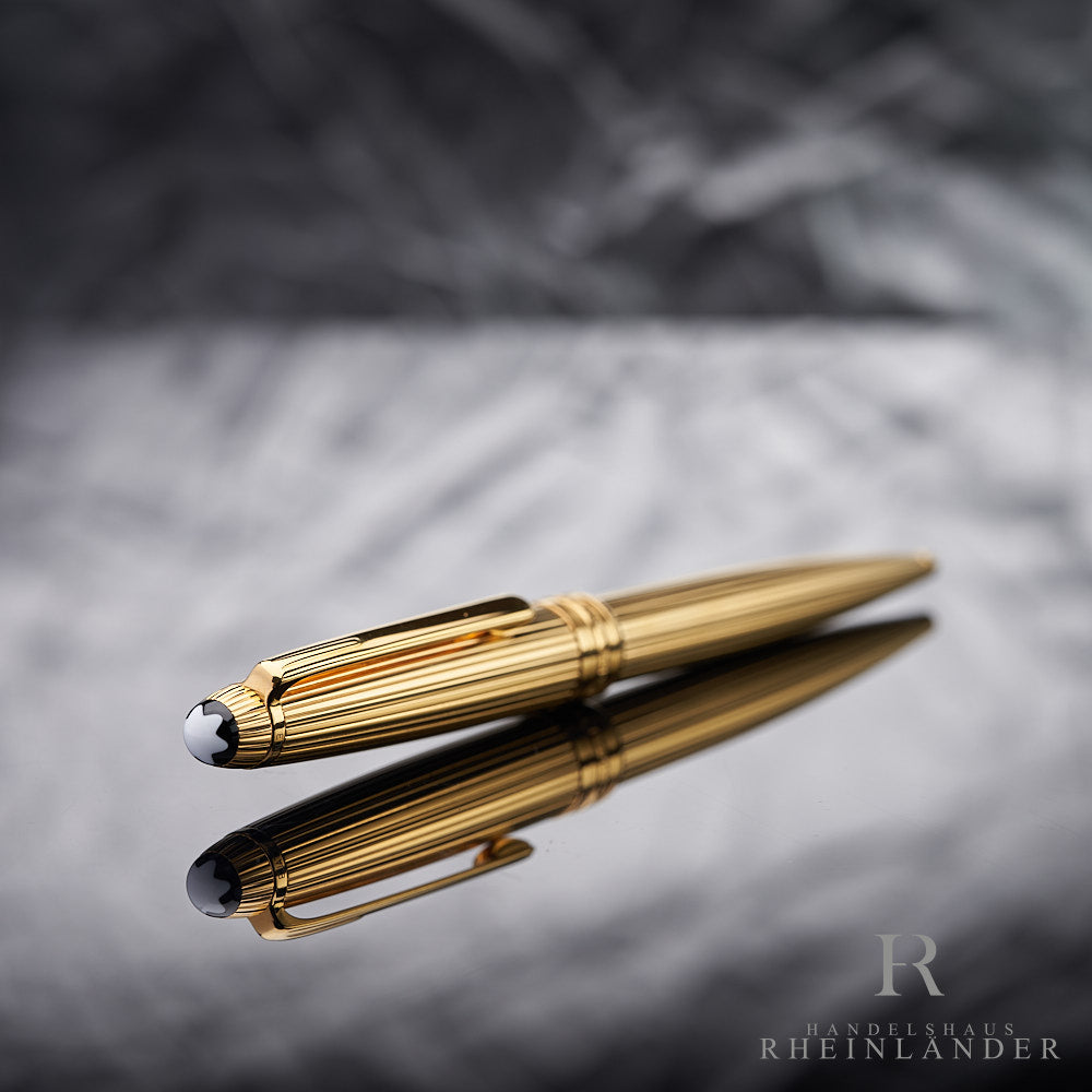 Kappenkopf mit Emblem des vergoldeten Montblanc Kugelschreiber mit Faden-Guilloche liegend vor silbernem Hintergrund