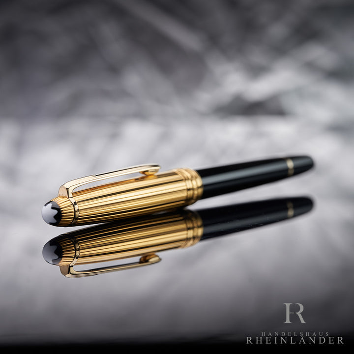 goldener Kappenkopf mit Emblem des Montblanc Solitaire Doue Gold Plated Rollerball liegend vor silbernem Hintergrund