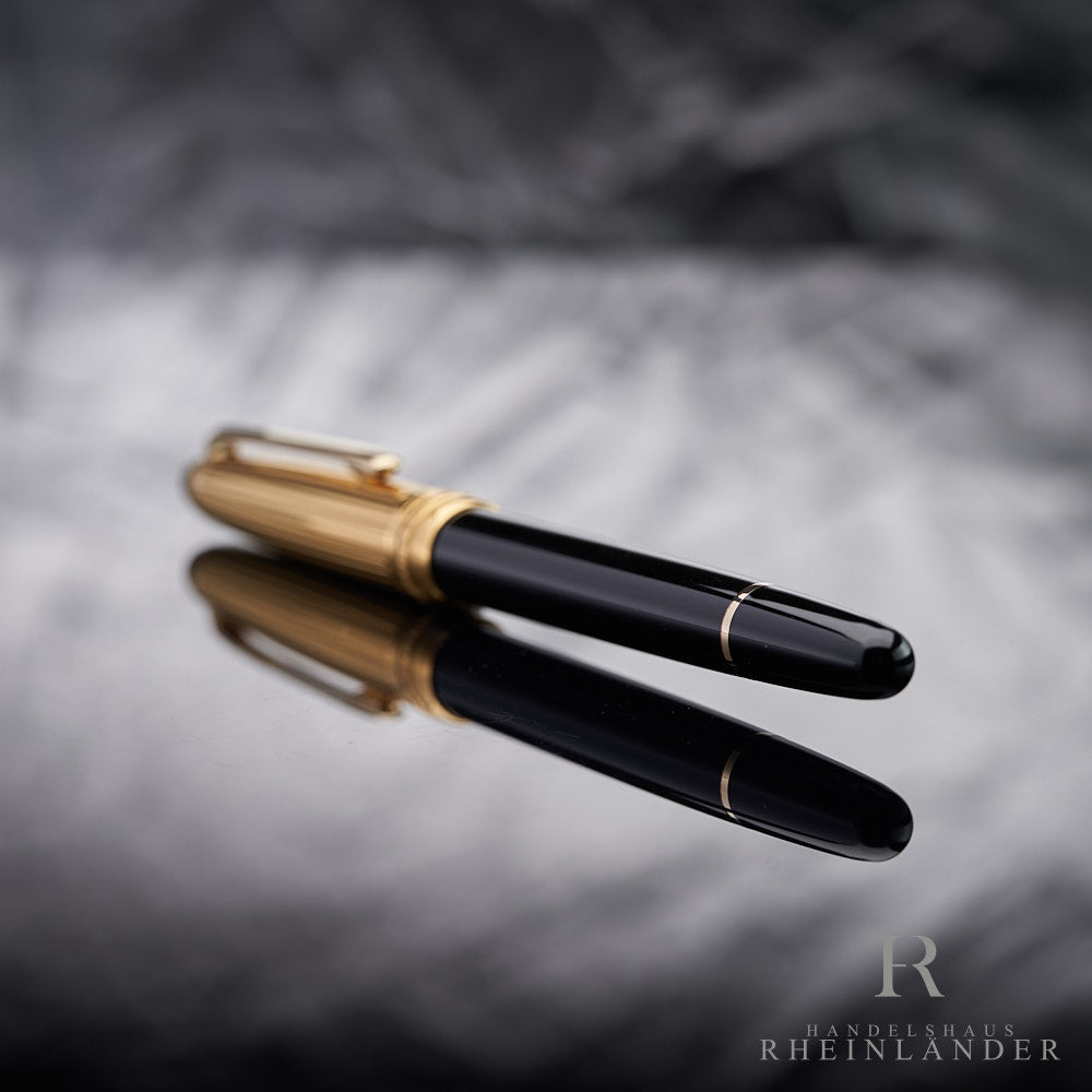 schwarzer Konus mit goldenem Ring des Solitaire Doue Classique Rollerballs liegend vor silbernem Hintergrund
