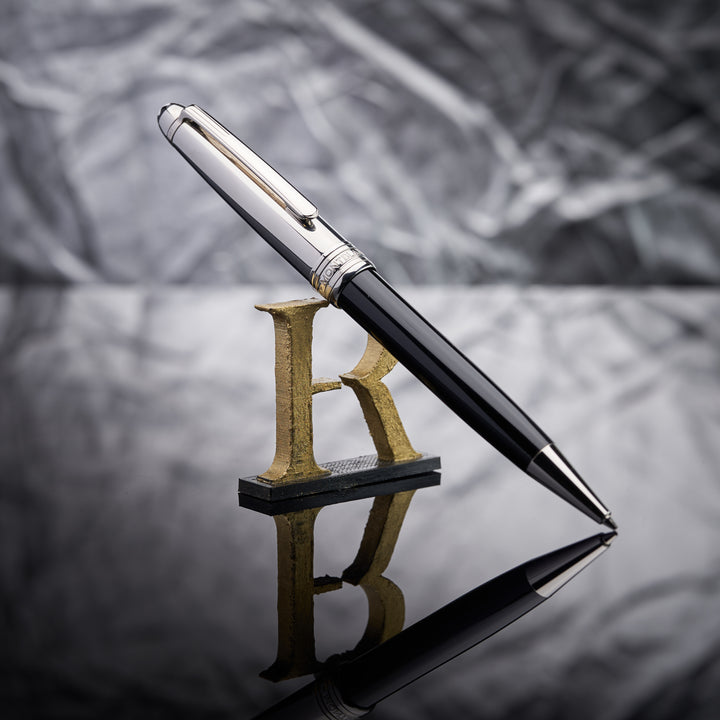 schwarzer Montblanc Bleistift mit Edelstahlkappe angelehnt an das Handelshaus Rheinländer Logo vor silbernem Hintergrund