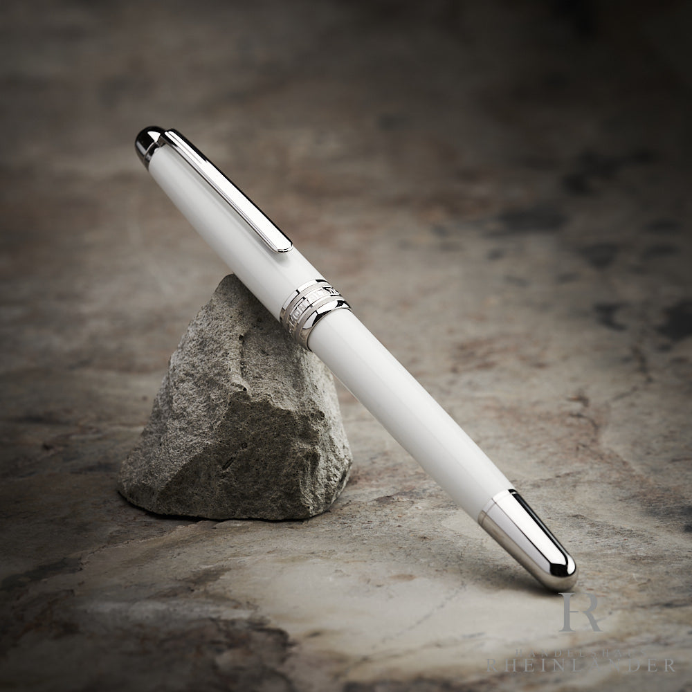 weißer Montblanc Tribute Rollerball mit silbernen Beschlägen angelehnt an einen Stein vor grauem Hintergrund