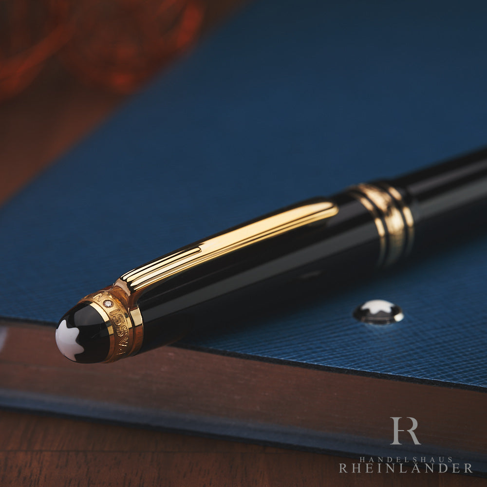 Kappenkopf mit Diamant und goldenem Clip eines Montblanc Füllers auf blauem Leder Notizbuch abgelegt
