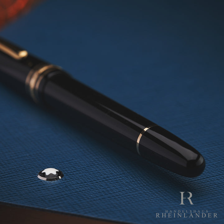 schwarzer Konus eines Montblanc Füllfederhalters liegend auf blauem Leder Notizbuch mit Montblanc Emblem