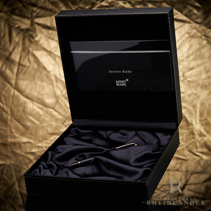 Schwarzer Füller von Montblanc mit roségoldenen Beschlägen in Originalbox mit Service Guide vor goldenem Hintergrund fotografiert
