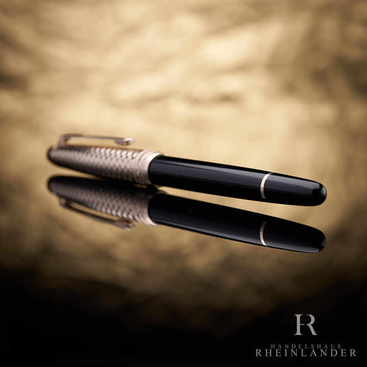 schwarzer Schaft und Konus-Ende des Montblanc Geometric Dimension Doue Rollerballs liegend vor goldenem Hintergrund