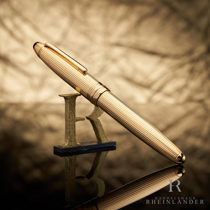 goldener Montblanc Rollerball mit Fadenguilloche angelehnt an das Handelshaus Rheinländer Logo vor goldenem Hintergrund