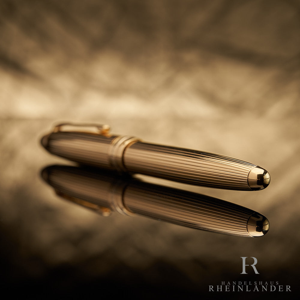 goldener Konus des Montblanc Vermeil LeGrand Rollerballs mit Fadenguilloche liegend vor goldenem Hintergrund
