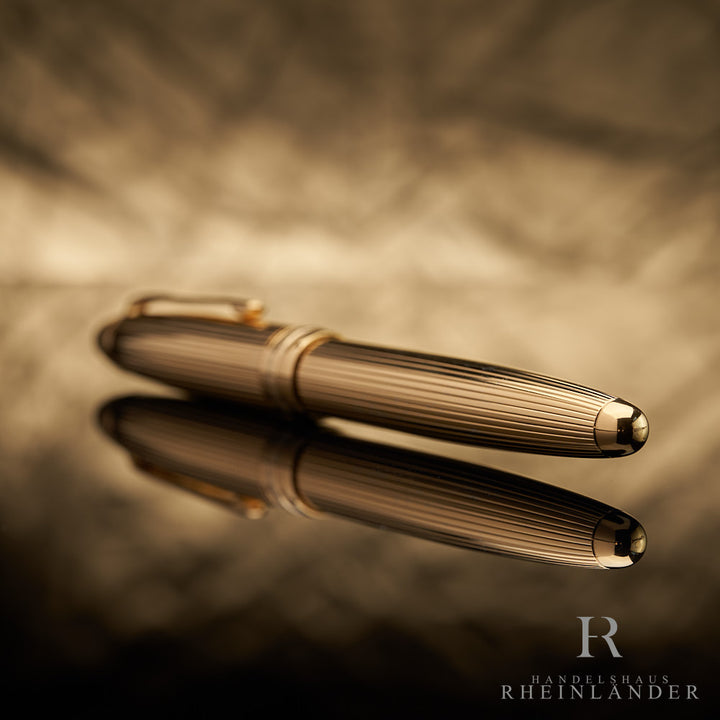 goldener Konus des Montblanc Vermeil LeGrand Rollerballs mit Fadenguilloche liegend vor goldenem Hintergrund