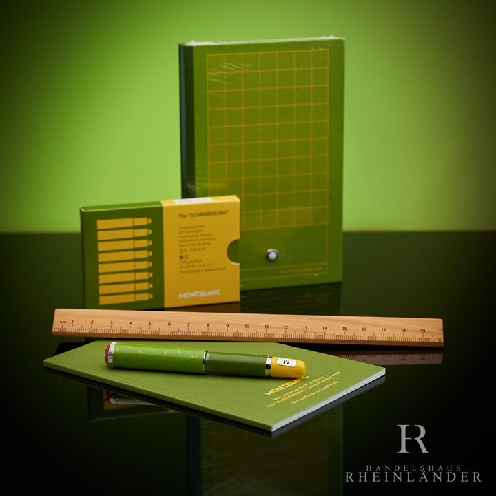 Montblanc Schreiberling Set bestehend aus Füller, Lineal, Patronen und Notizheft auf schwarzem Tisch vor grünem Hintergrund